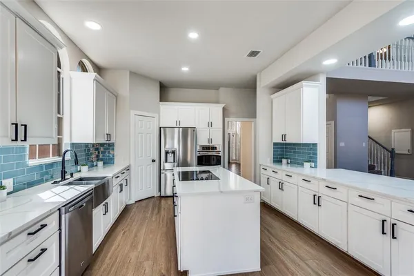a large kitchen with kitchen island a large counter space a sink appliances and cabinets