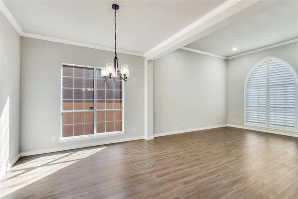 a view of an empty room with wooden floor and windows