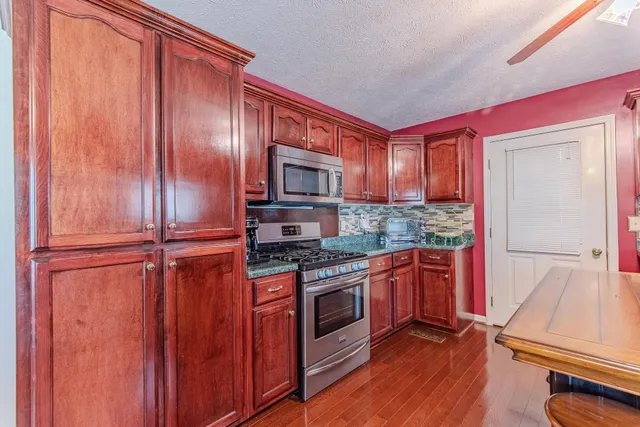 a kitchen with stainless steel appliances granite countertop wooden cabinets and a stove top oven