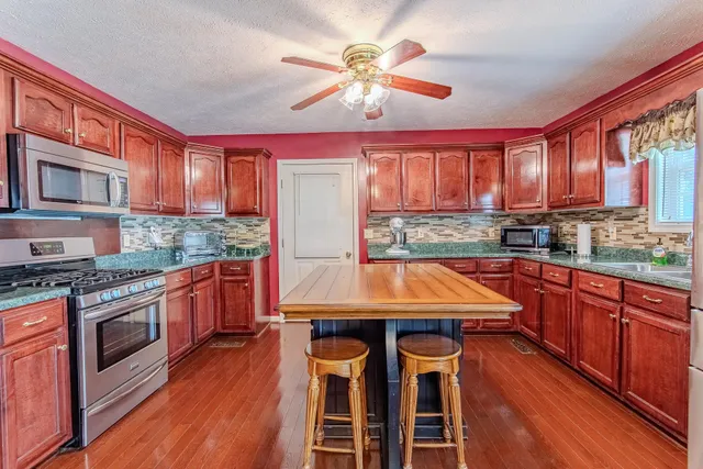 a kitchen with stainless steel appliances granite countertop wooden cabinets stove and refrigerator