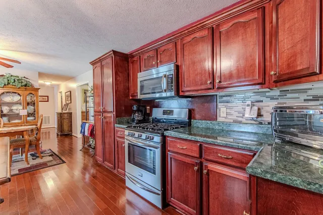 a kitchen with stainless steel appliances granite countertop wooden cabinets a stove a sink and dishwasher