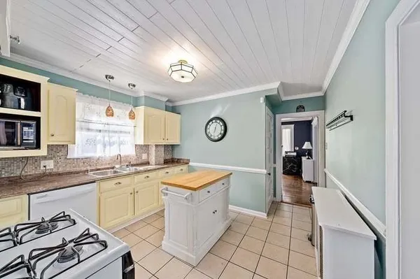 a large white kitchen with a stove a sink dishwasher and wooden cabinets