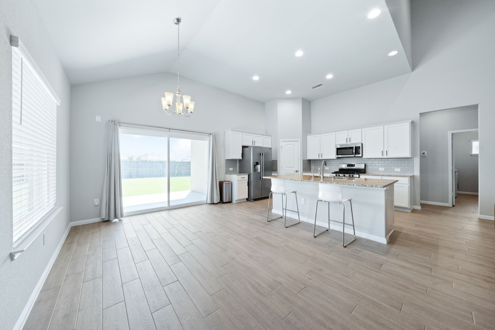 2412 Starhill Ranch Street Georgetown, TX 78628 - Photo 15 of 40 A well-lit open-concept living space with high ceilings and a functional kitchen island for gatherings.