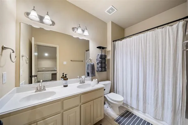 a bathroom with a double vanity sink toilet and a mirror