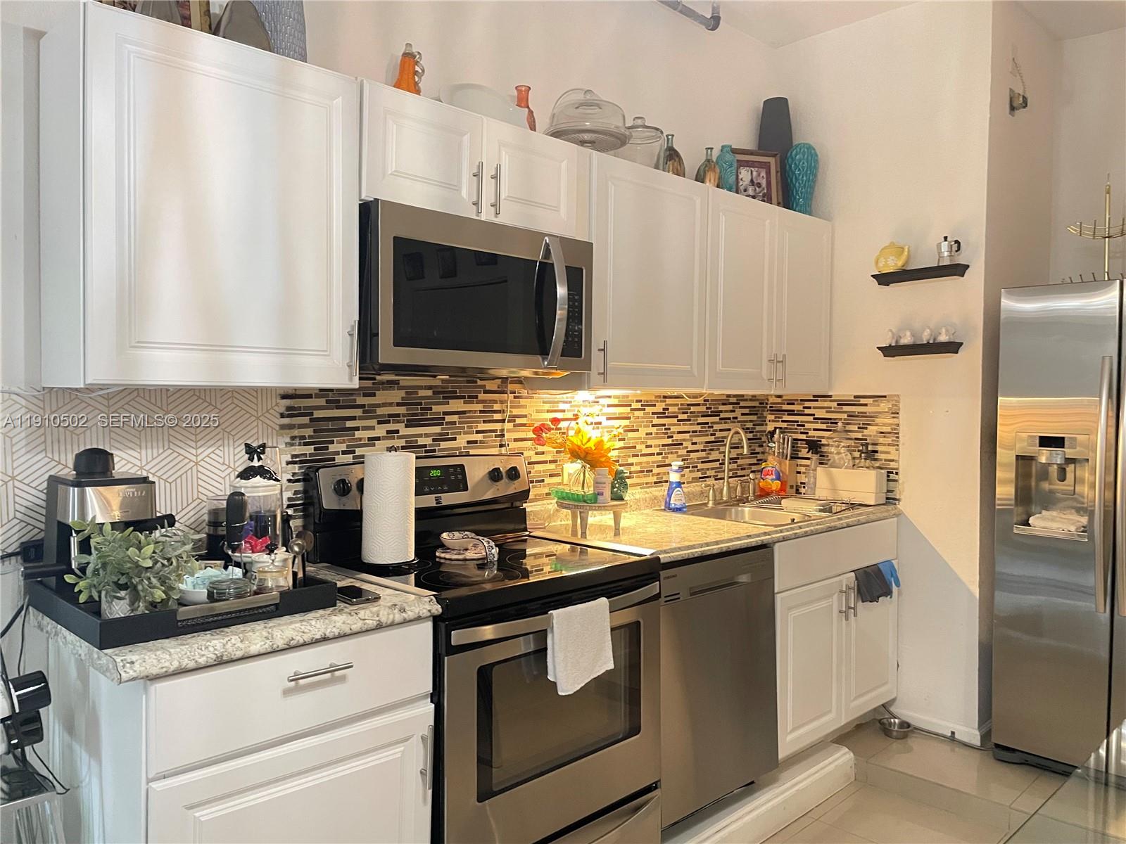 27563 Southwest 139th Place, Unit B Homestead, FL 33032 - Photo 4 of 17 a kitchen with stainless steel appliances granite countertop a sink stove and refrigerator