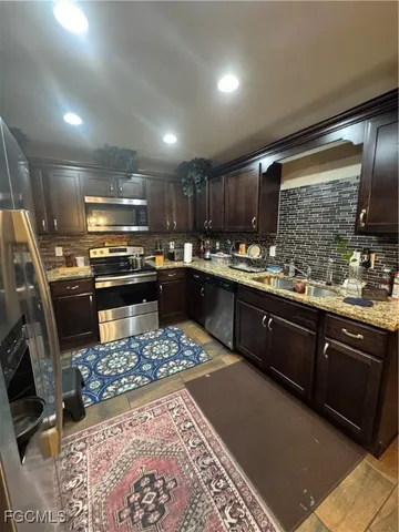 a kitchen with stainless steel appliances granite countertop a sink stove a refrigerator and cabinets