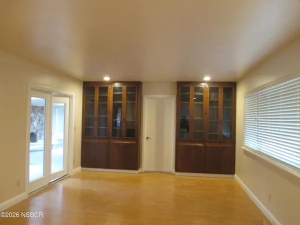 a view of an empty room with kitchen and window