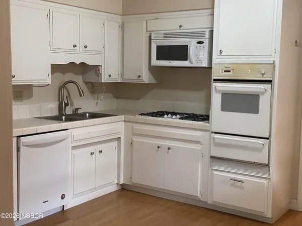 a kitchen with white cabinets and white appliances