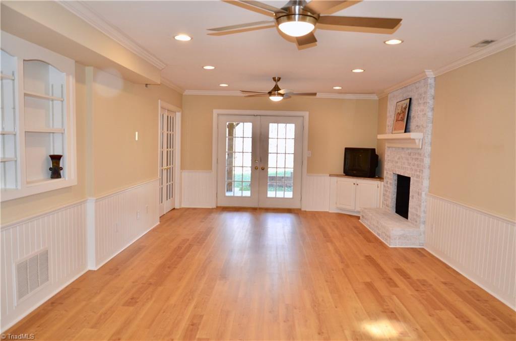 952 Bryanplace Road Winston-Salem, NC 27104 - Photo 25 of 30 Playroom/recreation room renovated over time: ceiling raised, recessed lighting added and and wetbar removed. 2020: whitewashed real masonry FP, new ceiling/light fans, and new LVP flooring (also extended down hallway/mudroom area closets and in bathroom; bathroom -new quartz vanity top new sink, faucet, light over sink, and new flooring. French doors added between playroom and unfinished area in garage and door added in back side of basement bathroom that opens to unfinished area as well.