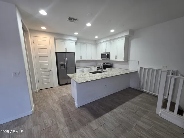 a kitchen with stainless steel appliances granite countertop a refrigerator sink and wooden cabinets