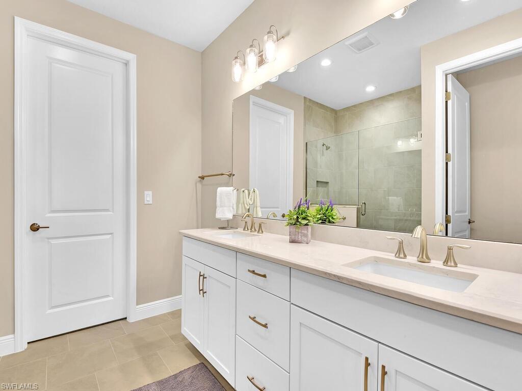 2561 Seychelles Drive, Unit 308 Naples, FL 34112 - Photo 11 of 28 a bathroom with a double vanity sink and a mirror