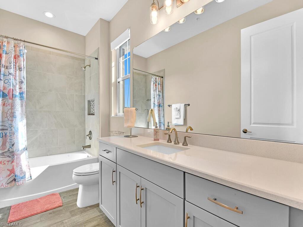 2561 Seychelles Drive, Unit 308 Naples, FL 34112 - Photo 14 of 28 a bathroom with a double vanity sink toilet mirror and bathtub