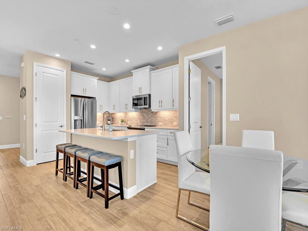 2561 Seychelles Drive, Unit 308 Naples, FL 34112 - Photo 3 of 28 a kitchen with kitchen island a stove a table and chairs in it