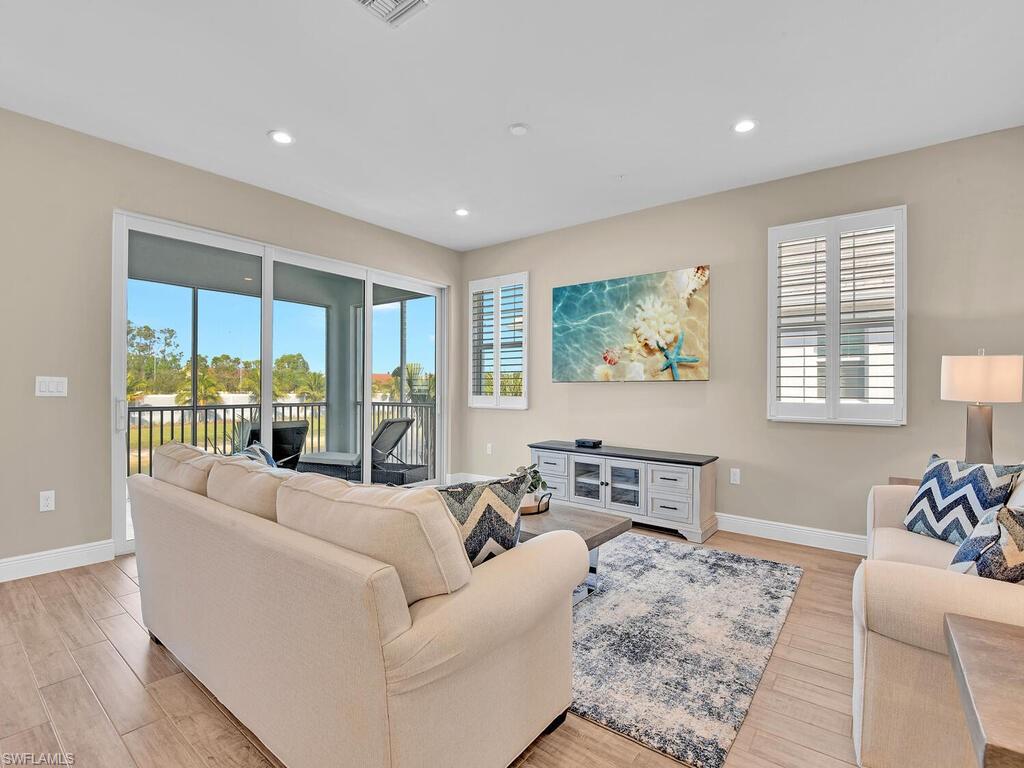 2561 Seychelles Drive, Unit 308 Naples, FL 34112 - Photo 5 of 28 a living room with furniture large windows and wooden floor