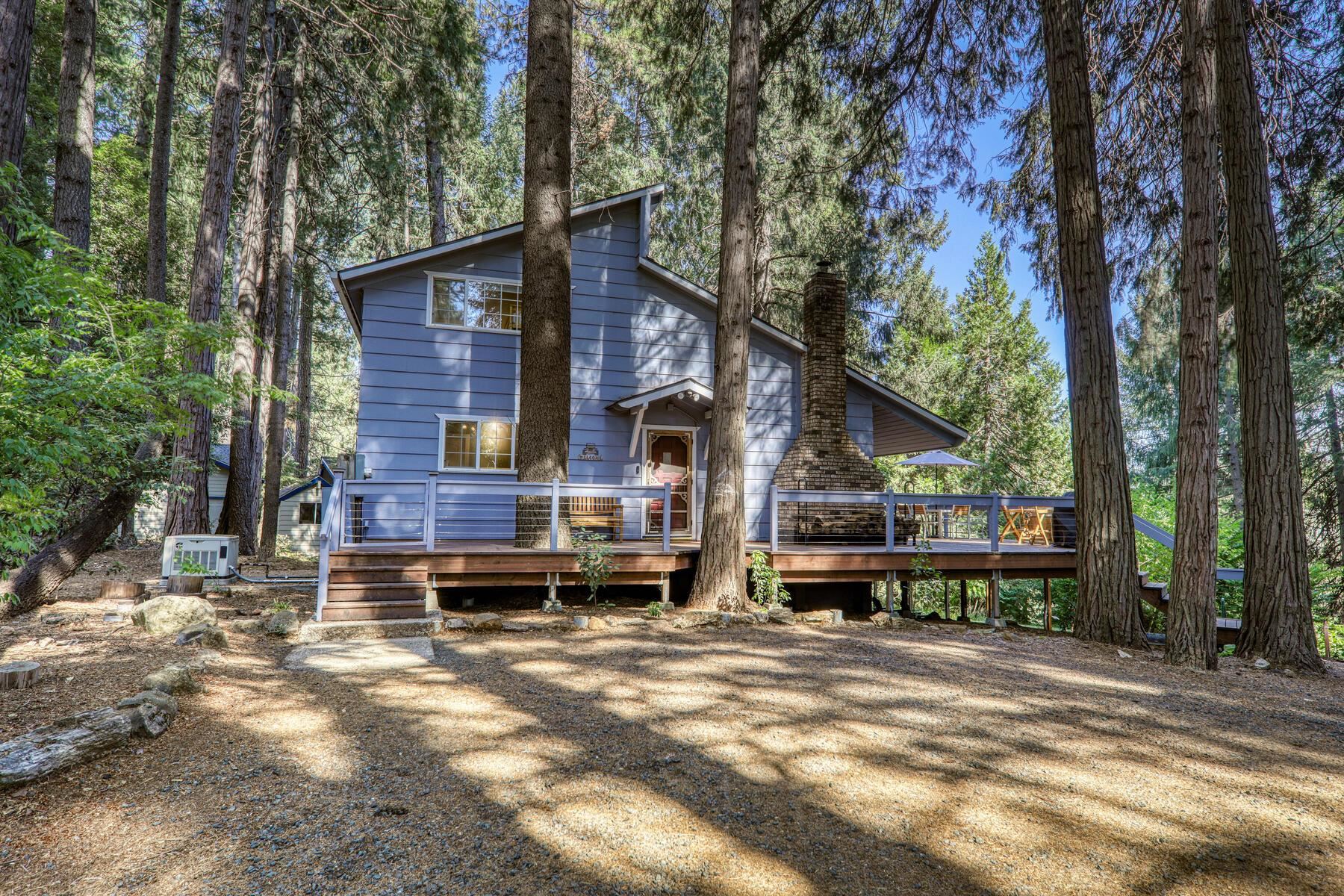 a view of a house with large trees and wooden fence