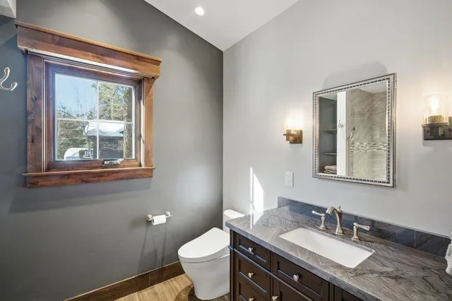 a bathroom with a granite countertop bathtub sink vanity mirror and toilet