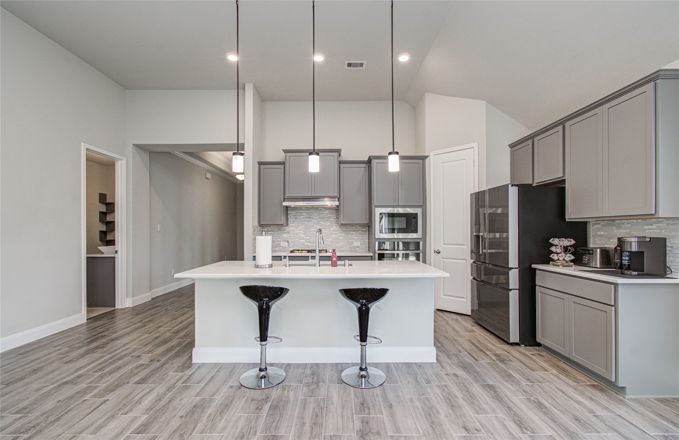 17344 Grand Canyon Road Conroe, TX 77302 - Photo 17 of 49 This modern kitchen features sleek gray cabinets, stainless steel appliances,quartz contertops, and a stylish center island with pendant lighting and barstools. The open layout and neutral tones create a spacious and inviting atmosphere, perfect for cooking and entertaining.