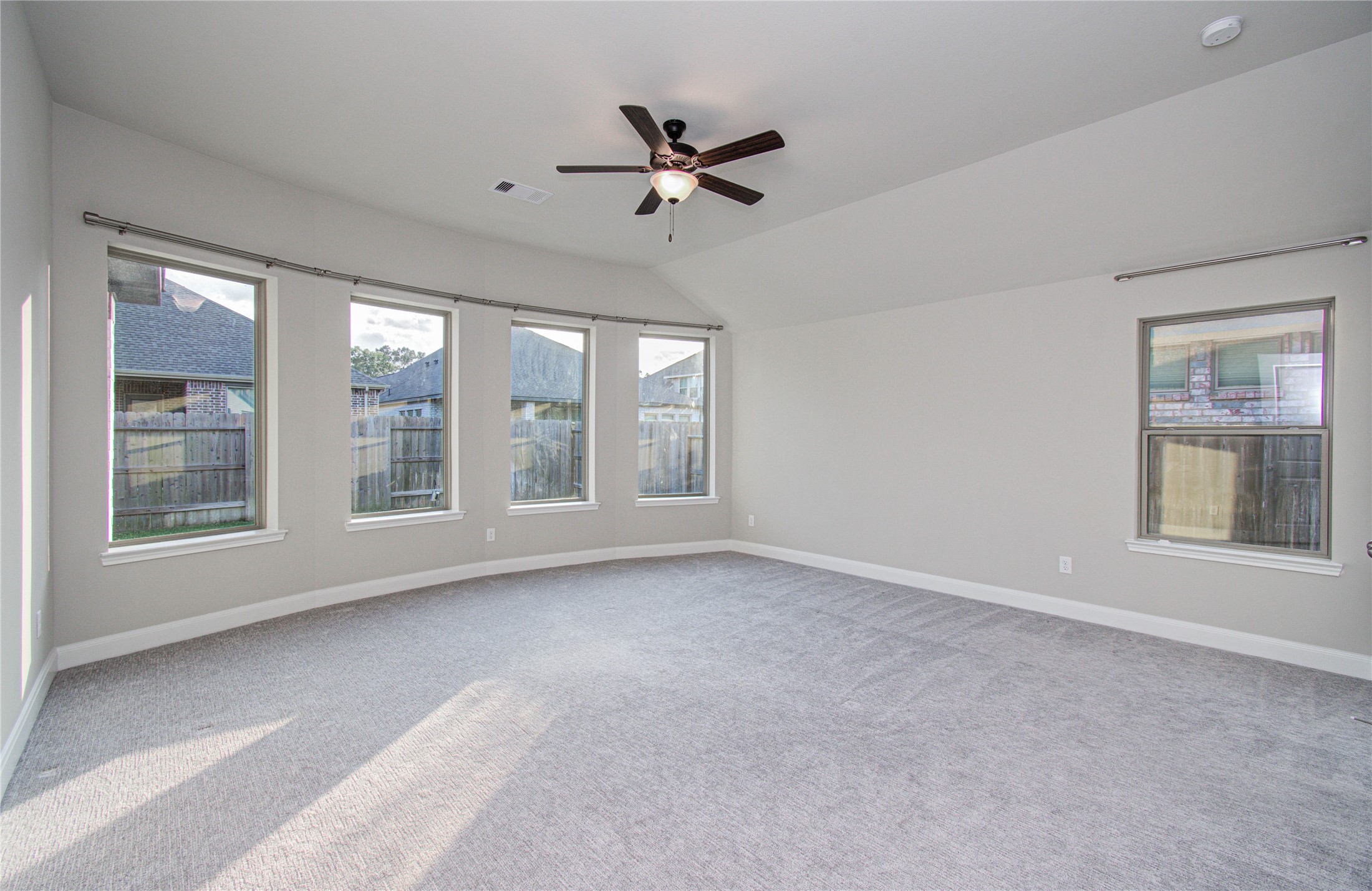 17344 Grand Canyon Road Conroe, TX 77302 - Photo 23 of 49 Spacious, carpeted room with abundant natural light from multiple windows, featuring a ceiling fan and neutral walls, ideal for a bedroom or living space.
