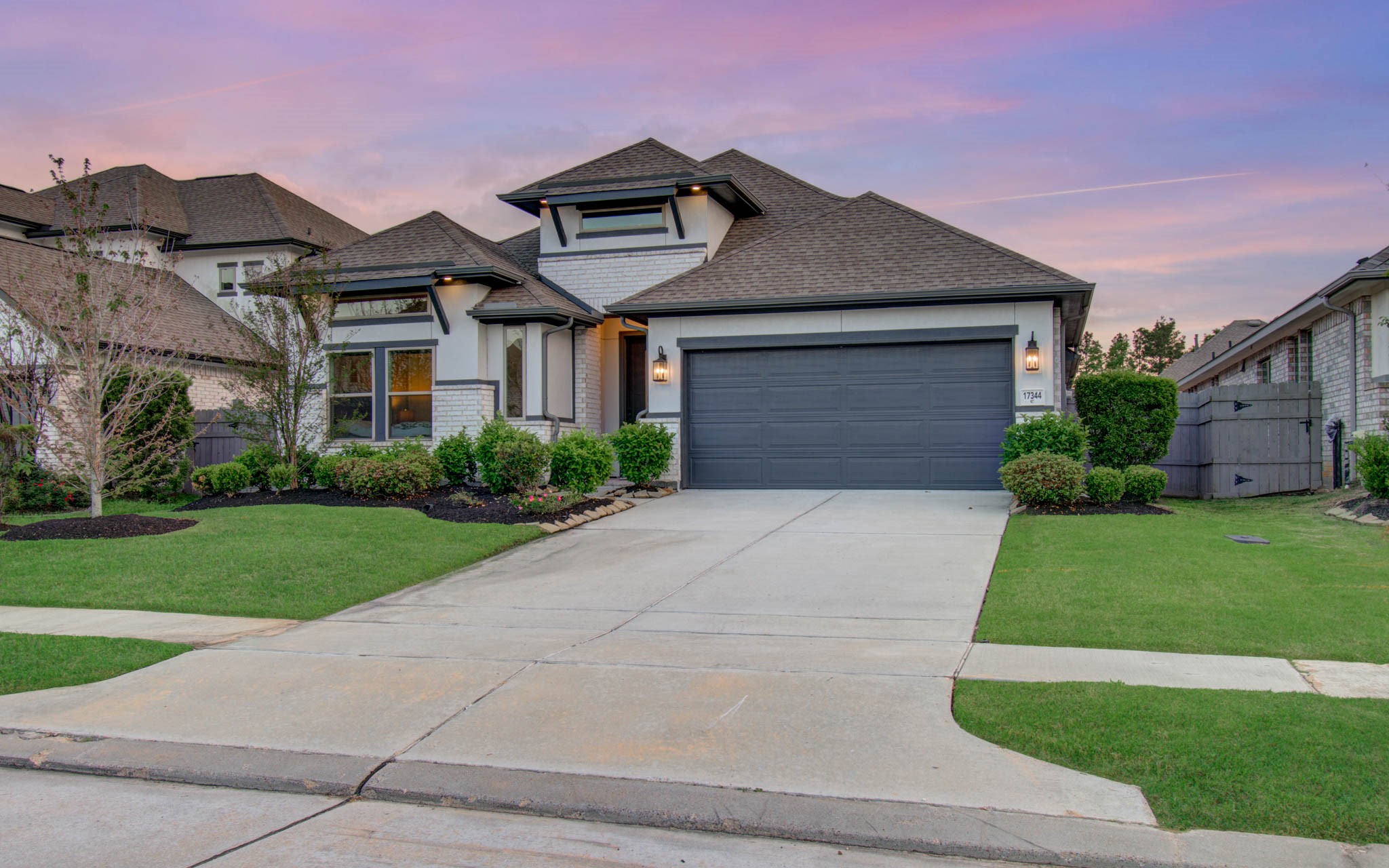 17344 Grand Canyon Road Conroe, TX 77302 - Photo 38 of 49 This charming home features a modern facade with a double garage, manicured lawn, and tidy landscaping. The sunset sky adds a warm backdrop, enhancing its curb appeal.