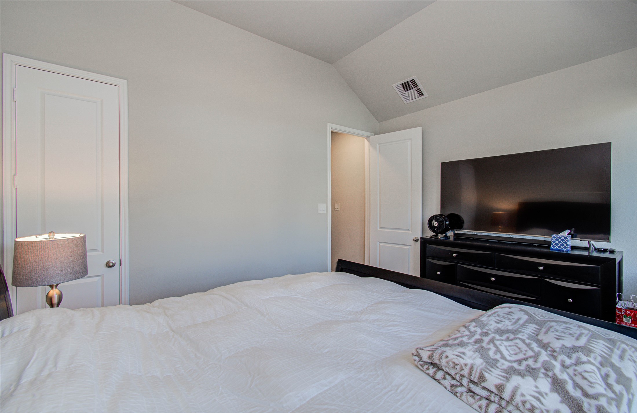 17344 Grand Canyon Road Conroe, TX 77302 - Photo 6 of 49 This bedroom features neutral walls, a large bed with cozy bedding, a dresser with a flat-screen TV, and a soft lamp for ambient lighting.
