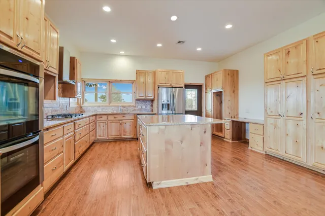 a large kitchen with stainless steel appliances granite countertop a lot of cabinets and wooden floor