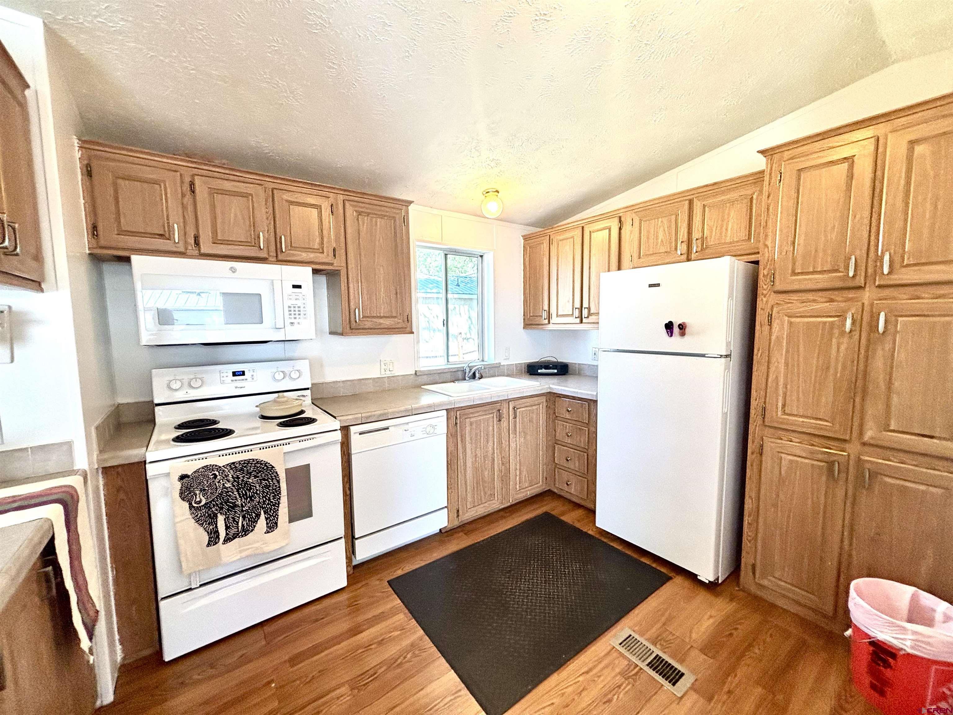 288 Animas View Drive, Unit 9 Durango, CO 81301 - Photo 10 of 16 a kitchen with a refrigerator a stove and wooden cabinets
