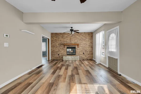 a view of a livingroom with wooden floor a fireplace and windows
