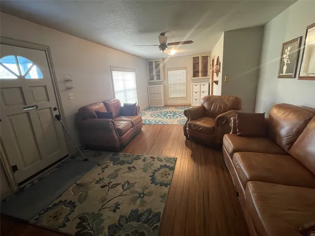 a kitchen with stainless steel appliances granite countertop a sink a stove a refrigerator a dining table and chairs with wooden floor