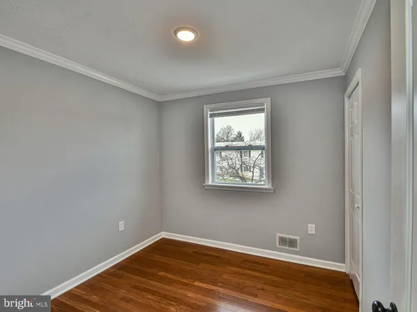 an empty room with wooden floor closet and windows