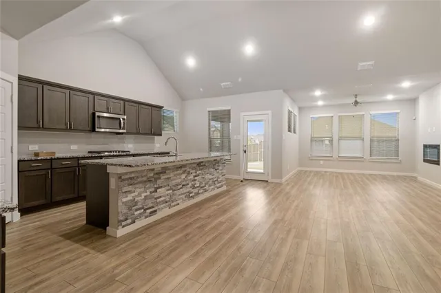 a kitchen with stainless steel appliances granite countertop a stove and a wooden floors