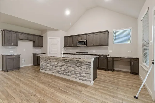a kitchen with stainless steel appliances granite countertop a stove a sink and a microwave
