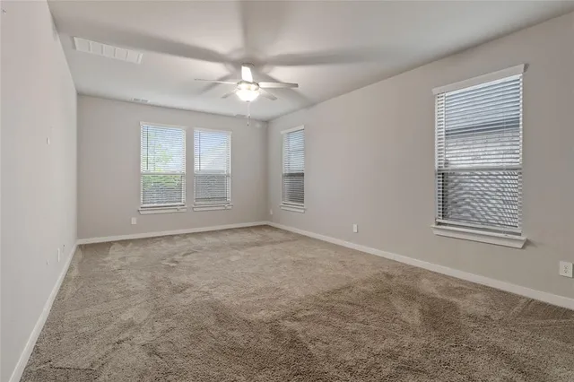 an empty room with chandelier fan and windows