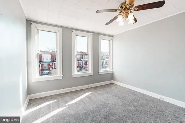 an empty room with windows and fan