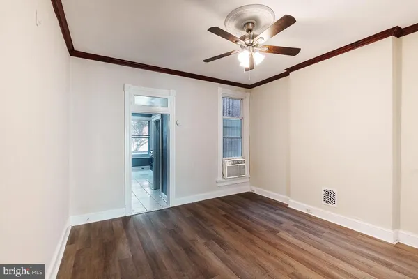 an empty room with wooden floor chandelier fan and windows
