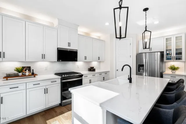 a kitchen with stainless steel appliances a stove a sink a microwave a counter space and cabinets