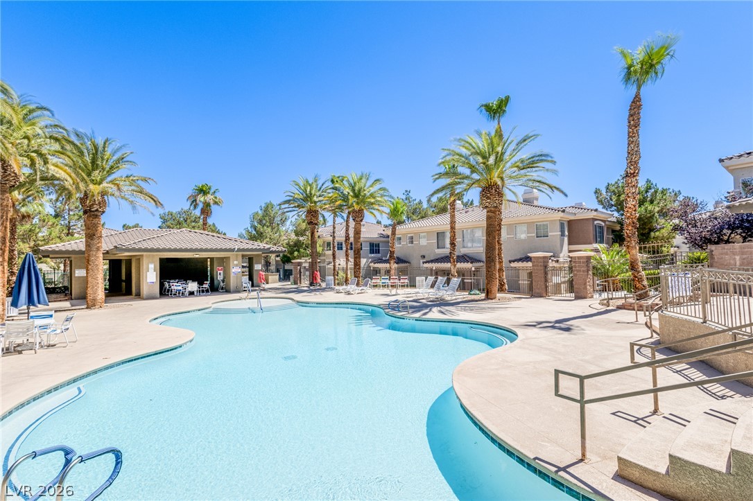 9050 West Warm Springs Road, Unit 1011 Las Vegas, NV 89148 - Photo 24 of 32 An inviting community pool with ample decking for relaxation is surrounded by mature palm trees.