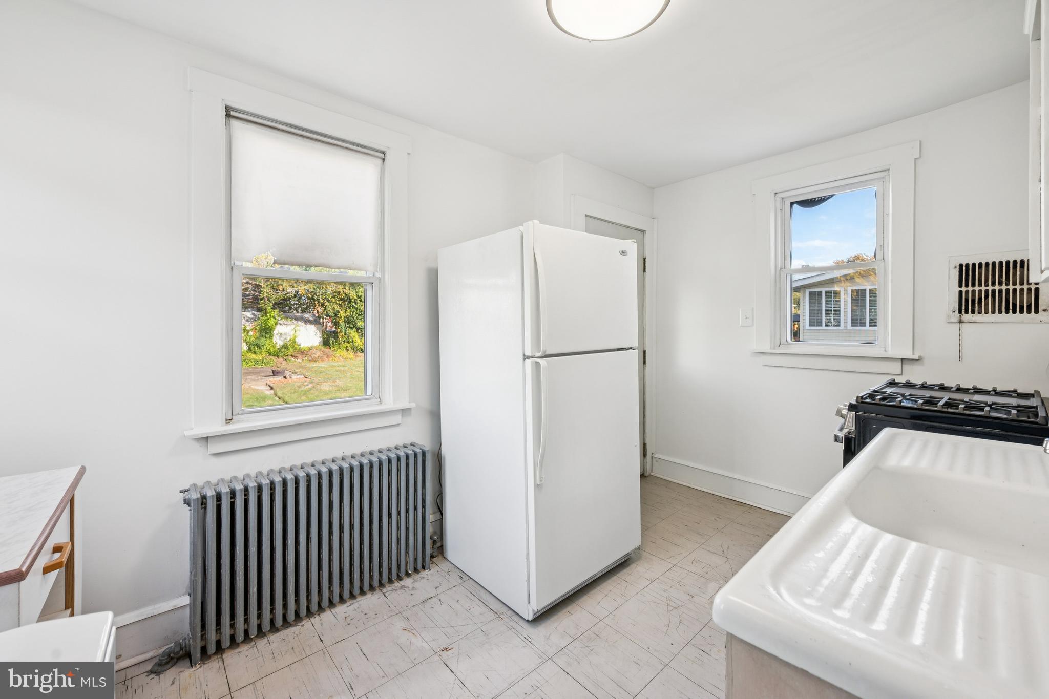 211 Newton Avenue Oaklyn, NJ 08107 - Photo 11 of 25 a view of a kitchen with a refrigerator a stove wooden floor and a window