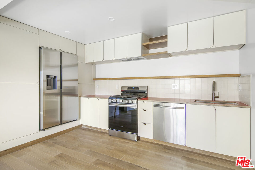 3361 Hamilton Way Los Angeles, CA 90026 - Photo 15 of 25 a kitchen with stainless steel appliances granite countertop a stove a refrigerator and a sink with cabinets