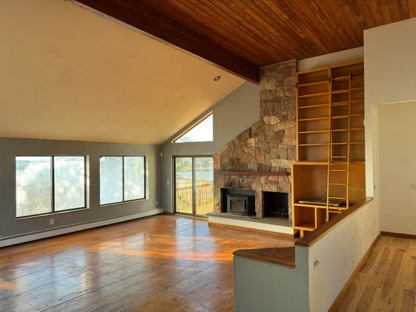 a view of an empty room with wooden floor and a fireplace