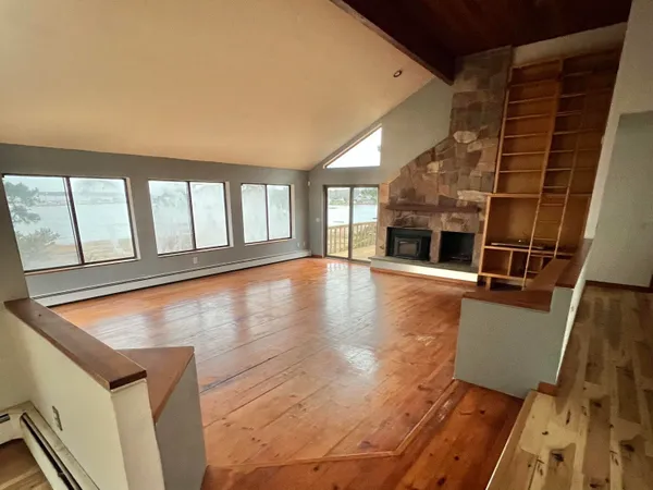 a view of an empty room with wooden floor and a fireplace
