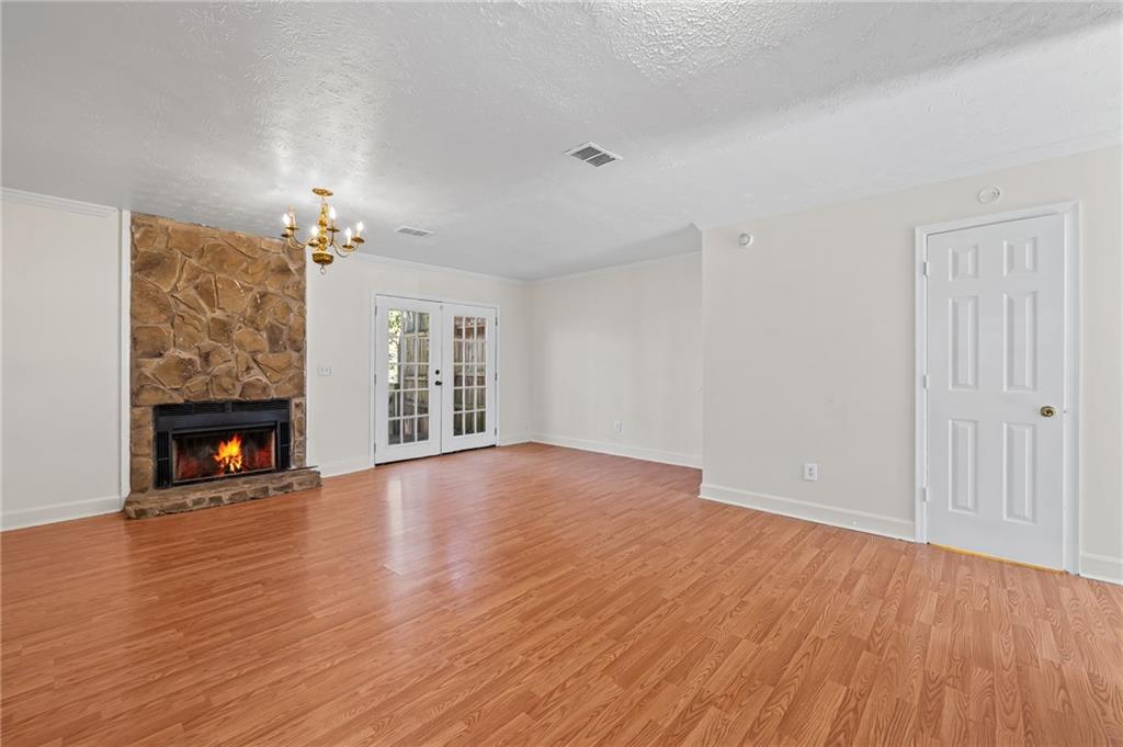 1222 Ridgecrest Lane Southeast Smyrna, GA 30080 - Photo 7 of 27 an empty room with wooden floor fireplace and chandelier