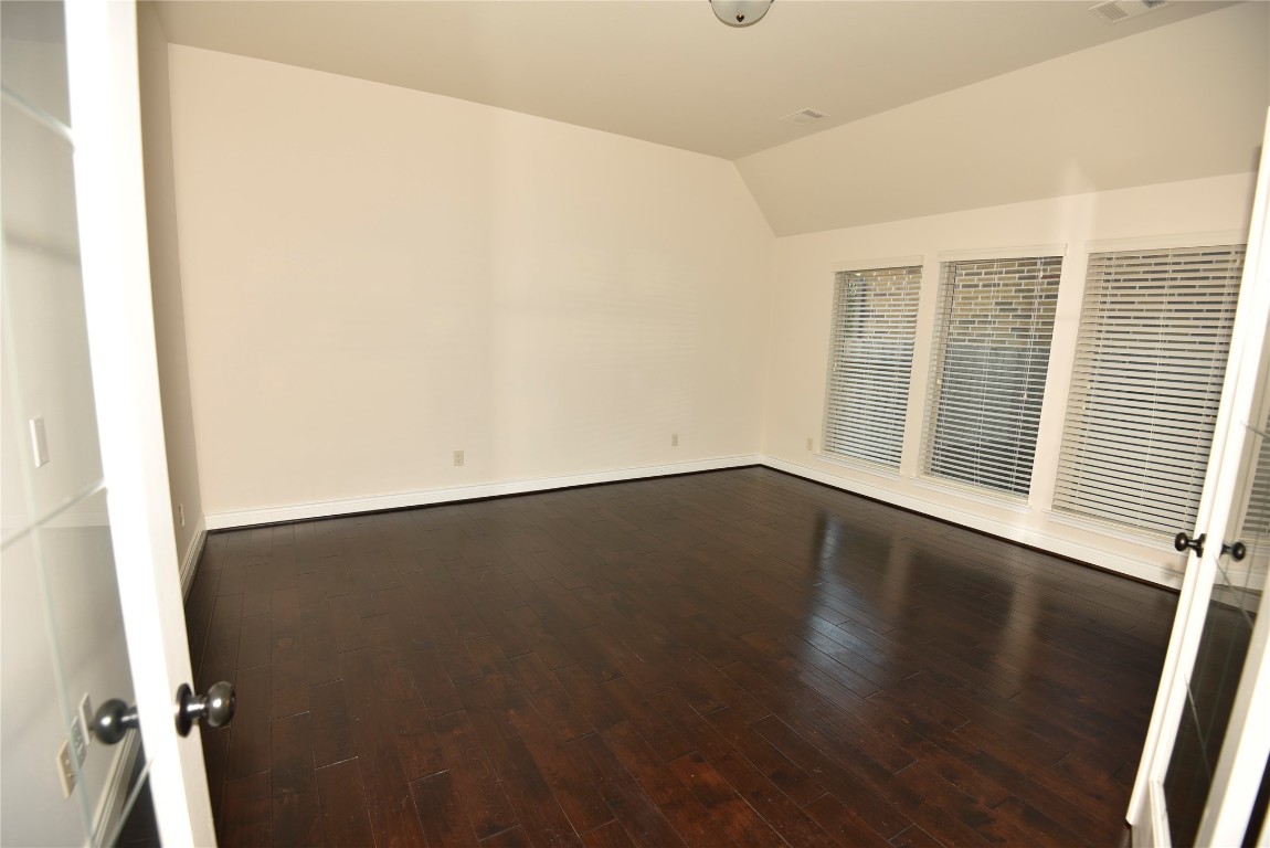18610 Lena Trail Drive Spring, TX 77388 - Photo 29 of 47 an empty room with wooden floor and windows with curtains