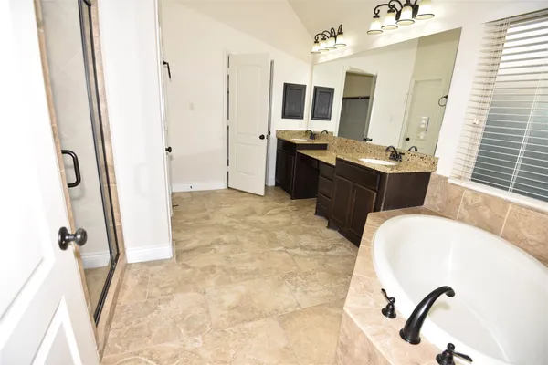 a large bathroom with a tub double vanity sink and mirror
