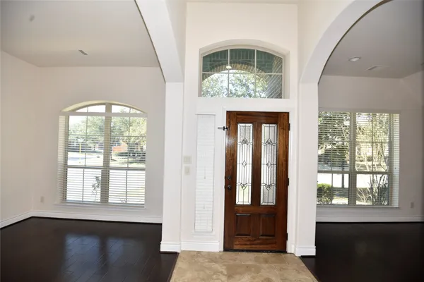 an empty room with wooden floor cabinet and windows