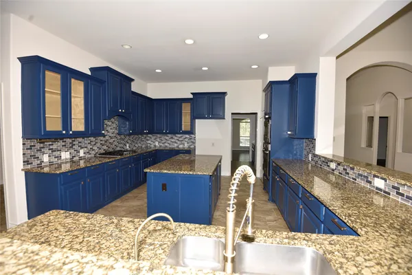 a kitchen with kitchen island granite countertop wooden cabinets a sink and stainless steel appliances
