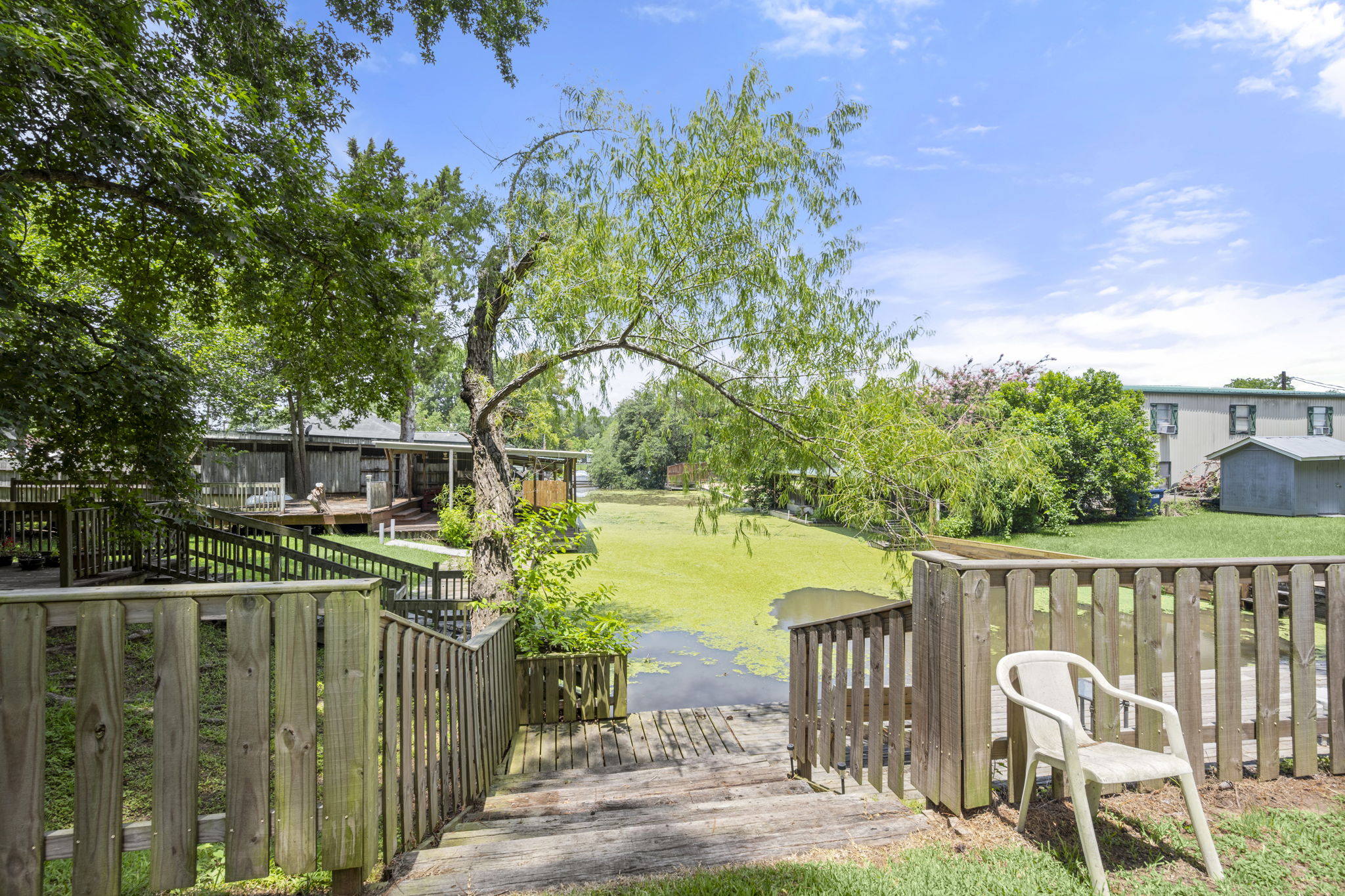 9649 Warm Spring Willis, TX 77318 - Photo 13 of 30 A wooden deck and dock extend to a serene pond, embraced by flourishing trees.