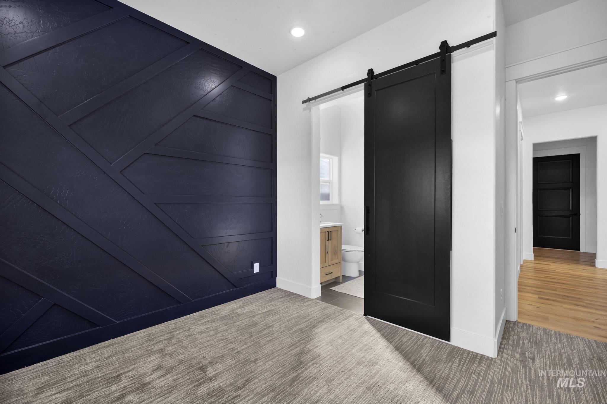 4280 Rim Vista Road Filer, ID 83328 - Photo 29 of 50 Accent wall featuring geometric paneling, black barn door, recessed lighting, and wood-finish flooring