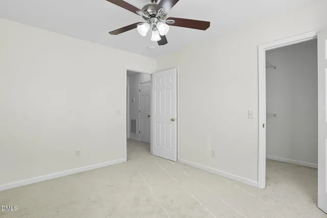 an empty room with closet and a chandelier fan