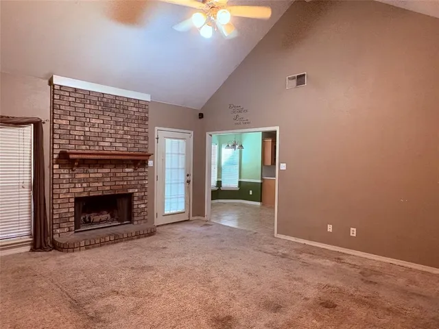 a view of an empty room with a fireplace and a window