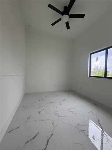an empty room with a ceiling fan and window
